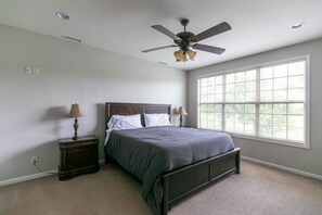 A bedroom with a bed, two bedside tables, a ceiling fan, and a large window. - Sleeps 14 on a Duck River ranch: 4 en suite bedrooms, patio, fishing, horses (Normandy)