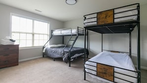 Une chambre avec des lits superposés, une commode et une fenêtre.