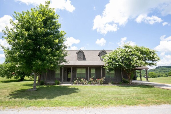 A two-story house with a front porch, a covered patio, and a large lawn. - Sleeps 14 on a Duck River ranch: 4 en suite bedrooms, patio, fishing, horses (Normandy)