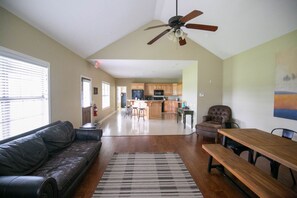 A spacious living room with a leather couch, a wooden dining table, and a ceiling fan. - Lakeview house on a 180-acre Duck River ranch: fishing, horses, bonfires (Normandy)