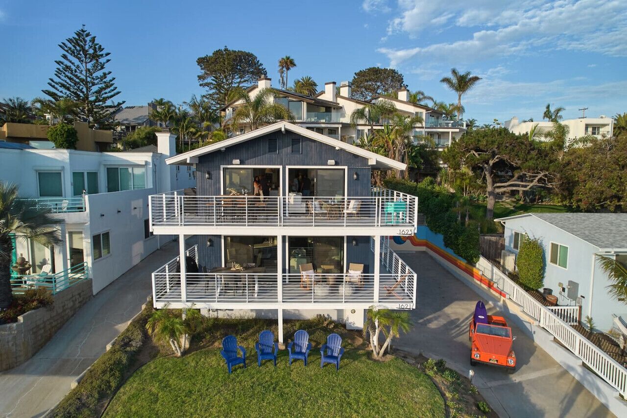 Une maison à deux étages avec un balcon, une allée et une voiture garée.