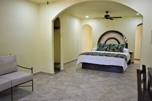 A bedroom with a bed, a chair, a ceiling fan, and a decorative wall arch.