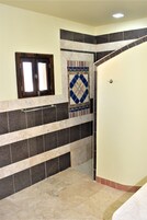 Un baño con suelo de baldosas, un perchero, una puerta y una ventana con marco de madera.
