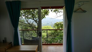 A room with a sliding glass door leading to a balcony with a view of greenery and mountains. - BUNGALOWS SANLAZ (Jesús)