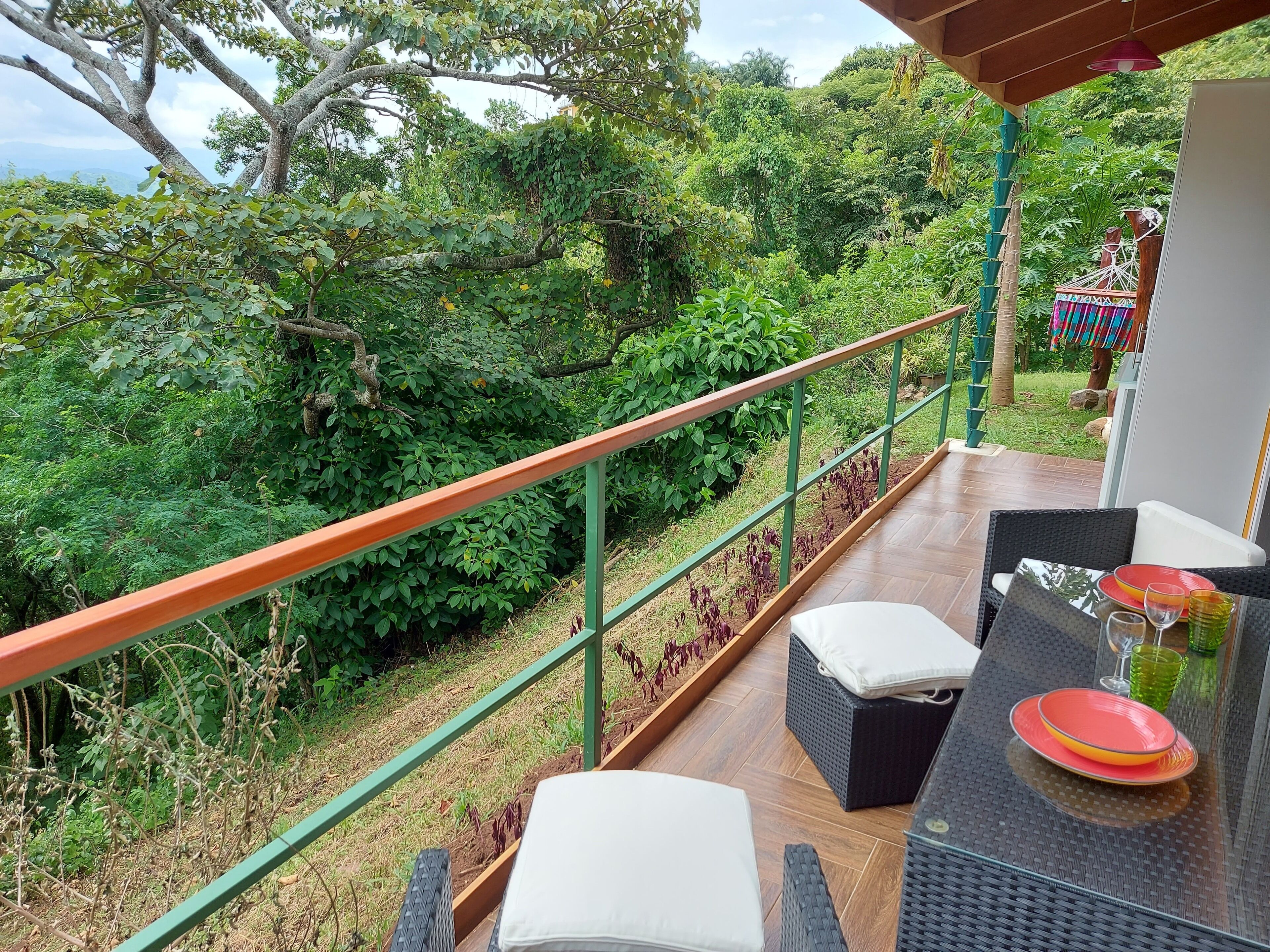 Un balcón con vistas a exuberante vegetación y una terraza de madera.
