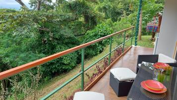 Un balcón con vistas a exuberante vegetación y una terraza de madera.