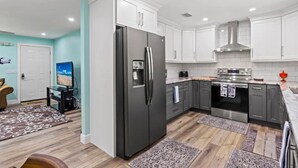 Una cocina moderna con armarios blancos, un refrigerador de acero inoxidable y un horno empotrado.