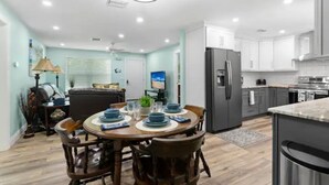 Una cocina moderna con armarios blancos, un refrigerador empotrado y un comedor con una mesa redonda y sillas.