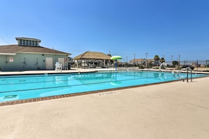 Relax by the pool surrounded by a covered seating area and a small building.