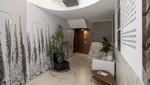 A modern lobby with a curved ceiling, a staircase, and a seating area with a plant. - In the city centre - Cine Park Residence I (Funchal)