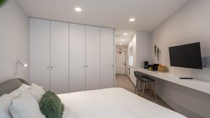Una habitació d'hotel moderna amb un llit gran, un escriptori amb cadira, una televisió i un armari.