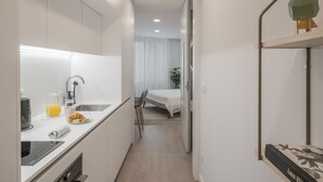 Una cuina compacta amb un disseny modern, que inclou forn encastrat, rentapelats i taulell amb torradora, un got de suc d'aranja i un plat amb menjar.