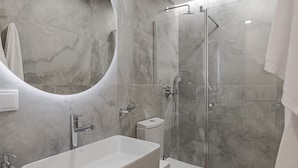 Ein modernes Badezimmer mit einem großen, rechteckigen Waschbecken, einer Duschkabine und einer Toilette.