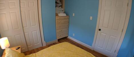 A bedroom with a bed, a dresser, and a ceiling fan.