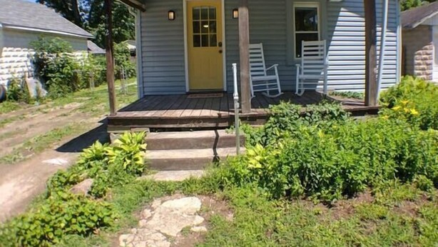 A small, single-story house with a front porch, a door, and a small window.