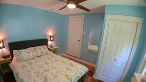 A bedroom with a bed, two bedside lamps, a ceiling fan, a door, and a mirror. - Harper, Two Bedroom House in Historic Loveland (Loveland)