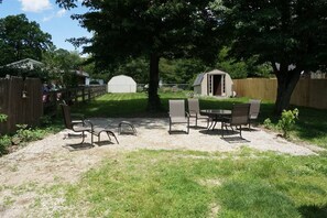 An outdoor patio area with a table and chairs, surrounded by a wooden fence and trees. - Harper, Two Bedroom House in Historic Loveland (Loveland)