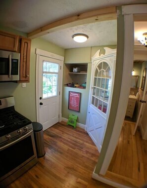 Una cocina compacta con armarios de madera, un fogón, un microondas y una ventana pequeña.