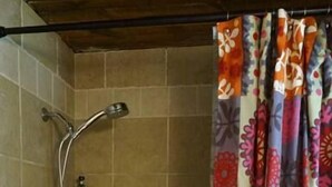 A bathroom with a bathtub, shower, and a shelf with a bottle. - Harper, Two Bedroom House in Historic Loveland (Loveland)