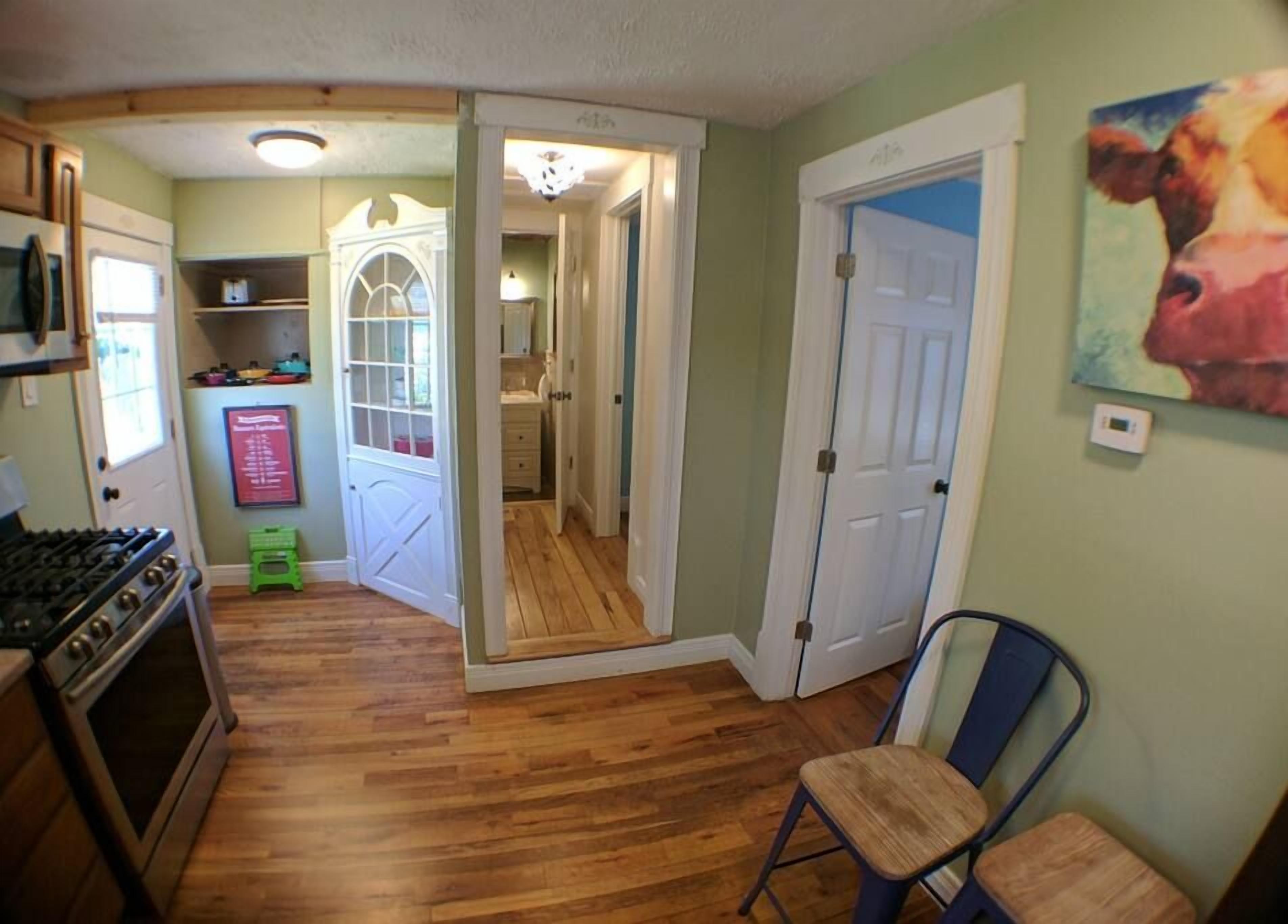 A compact kitchen with a stove, a refrigerator, and a dining area with a chair.