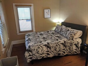 A bedroom with a bed, a window with blinds, a bedside lamp, and a framed picture on the wall. - Ohio Ave, 3 bed house, Historic Downtown Loveland (Loveland)