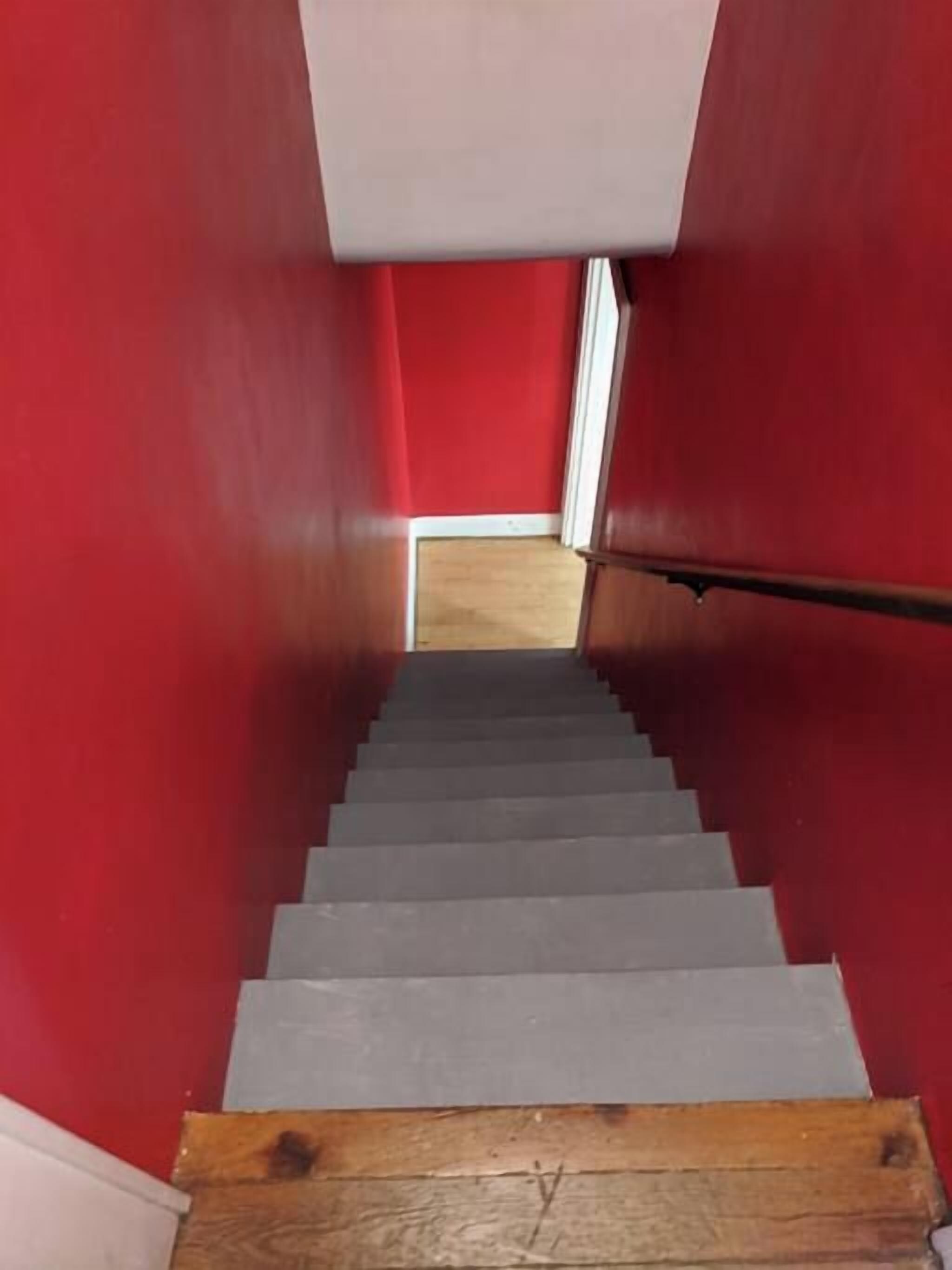 A staircase with red walls and a wooden handrail.
