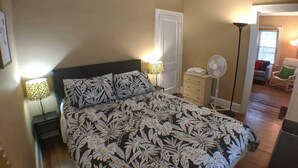 A bedroom with a large bed, two bedside lamps, a dresser, a fan, and a chair. - Ohio Ave, 3 bed house, Historic Downtown Loveland (Loveland)
