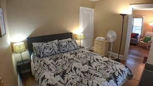 A bedroom with a large bed, two bedside lamps, a dresser, a fan, and a chair. - Ohio Ave, 3 bed house, Historic Downtown Loveland (Loveland)
