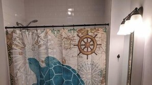 A bathroom with a sea turtle-themed shower curtain, a white toilet, and a sink with a mirror. - Ohio Ave, 3 bed house, Historic Downtown Loveland (Loveland)
