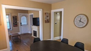 A dining area with a round table, four chairs, a clock on the wall, and a fireplace. - Ohio Ave, 3 bed house, Historic Downtown Loveland (Loveland)