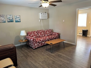 A living room with a red floral sofa, a wooden coffee table, a lamp, and a ceiling fan.