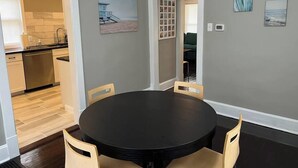 A dining area with a round table and chairs, a kitchen in the background, and artwork on the walls. - Ridgeway, 2 Bedroom House near Xavier, Downtown (Cincinnati)