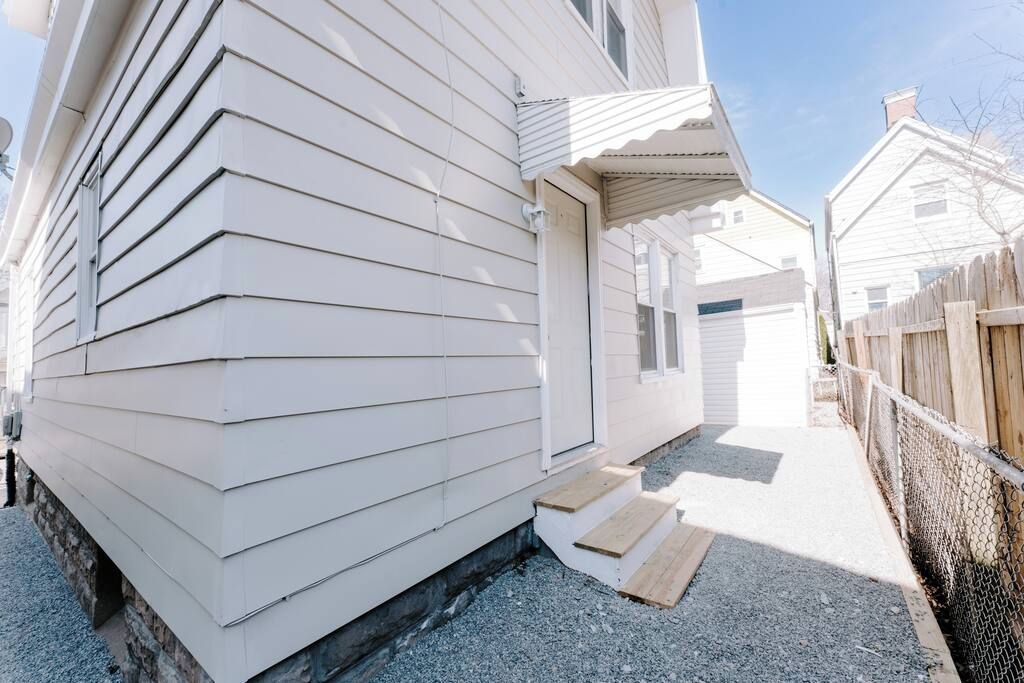 A single-story house with a front porch, a small set of steps leading to the door, and a chain-link fence along the side.