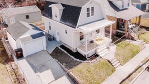 Uma casa de dois andares com garagem, varanda coberta e um pequeno quintal.