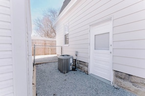 A residential outdoor area with a white garage door, a gray air conditioning unit, and a gravel driveway. - Ridgeway, 2 Bedroom House near Xavier, Downtown (Cincinnati)