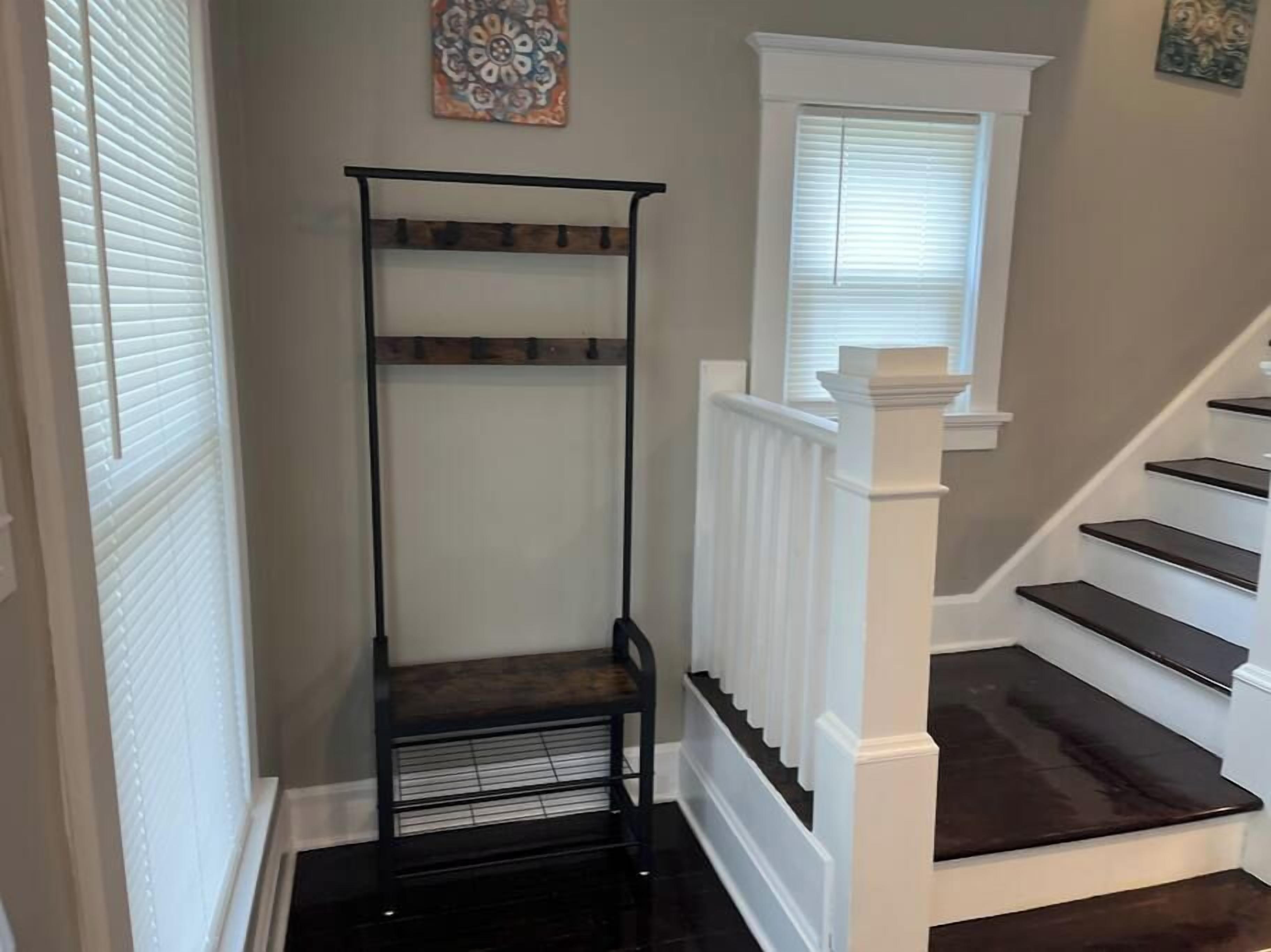 A staircase with white railings and dark steps, a black metal shelf unit, and a decorative wall piece.