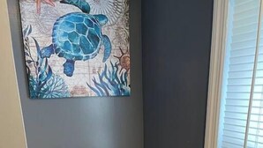 A bathroom with a toilet, a roll of toilet paper, and a wall-mounted painting of a turtle. - Ridgeway, 2 Bedroom House near Xavier, Downtown (Cincinnati)