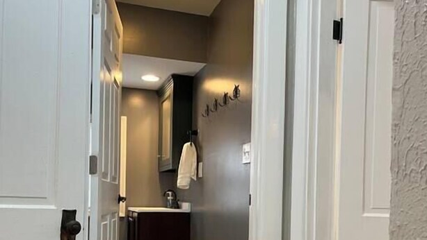 Um corredor com piso escuro, portas brancas e tapete em tons claros.