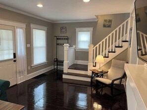 A spacious living room with hardwood floors, a staircase, and a seating area. - Ridgeway, 2 Bedroom House near Xavier, Downtown (Cincinnati)