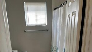 A narrow bathroom with a toilet, a towel rack, and a shower curtain.
