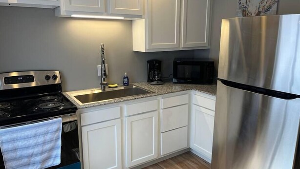 A kitchen with white cabinets, a stainless steel refrigerator, a microwave, a stove, and a sink. - Carter #4, Two bedroom unit near Xavier, Downtown (Cincinnati)