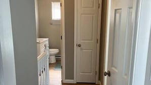 A narrow hallway with wooden flooring leading to a bathroom with a toilet and a window. - Carter #4, Two bedroom unit near Xavier, Downtown (Cincinnati)