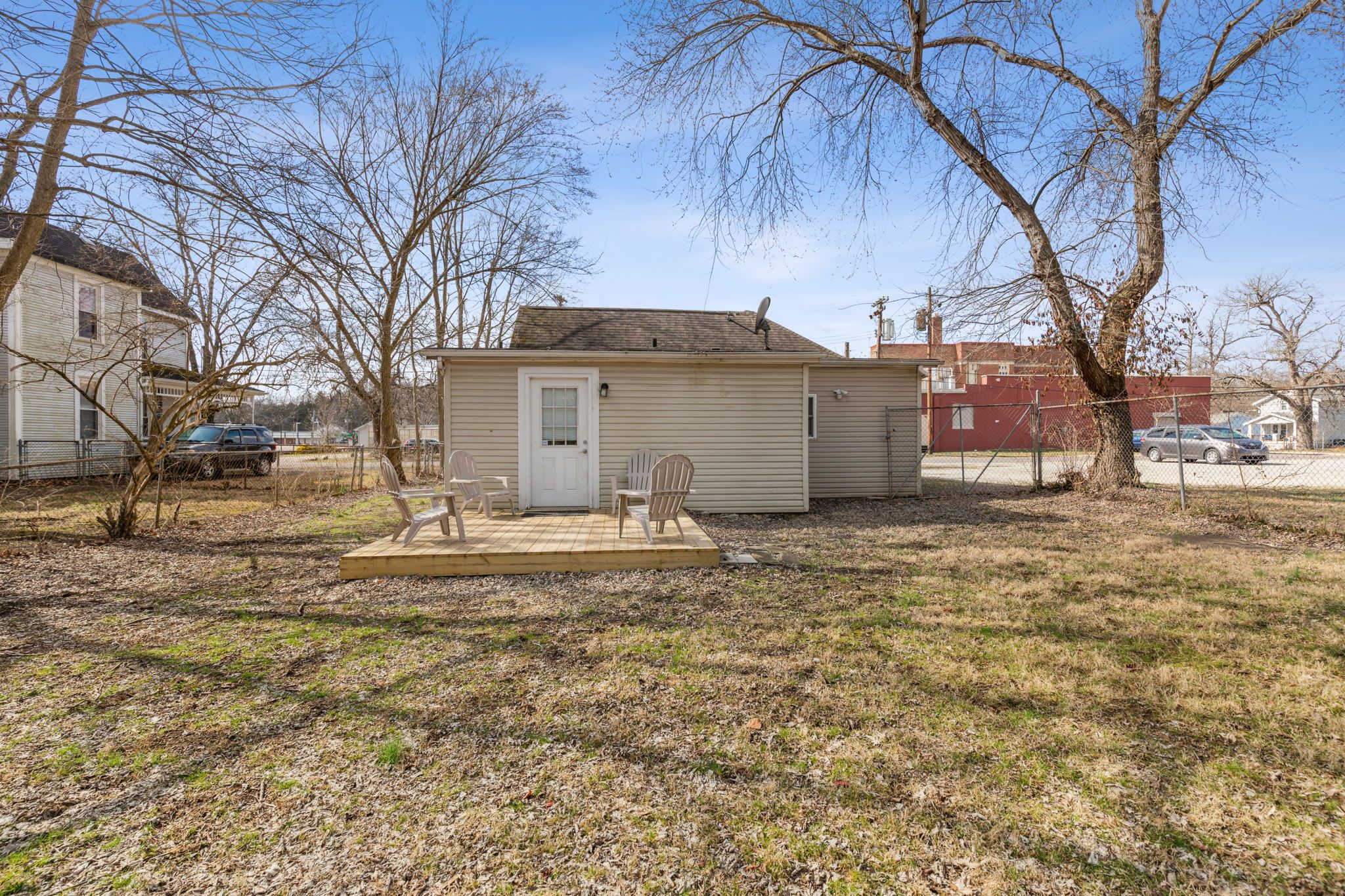 A small, single-story house with a front porch, a satellite dish, and a fenced yard.