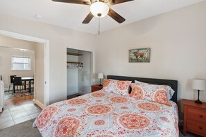 A bedroom with a bed, a ceiling fan, a nightstand, and a door leading to a bathroom. - Chestnut, Three Bedroom House in Historic Loveland (Loveland)
