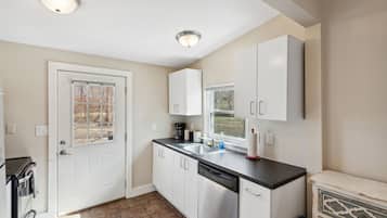 A modern kitchen with white cabinets, a black countertop, and a dishwasher.