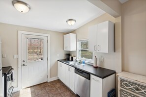 A modern kitchen with white cabinets, a black countertop, and a dishwasher.