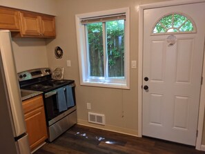 A kitchen with a stove, oven, and cabinets, a window with a view of trees, and a white door. - Carter #5, Private Two Bed near Xavier, Downtown (Cincinnati)