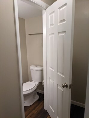 A bathroom with a toilet, a white door, and wooden flooring. - Carter #5, Private Two Bed near Xavier, Downtown (Cincinnati)