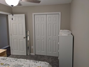 A bedroom with a bed, two white doors, a ceiling fan, and a white cabinet.