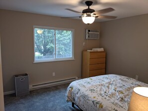 Quarto com cama, cômoda, janela, ventilador de teto e aquecedor.